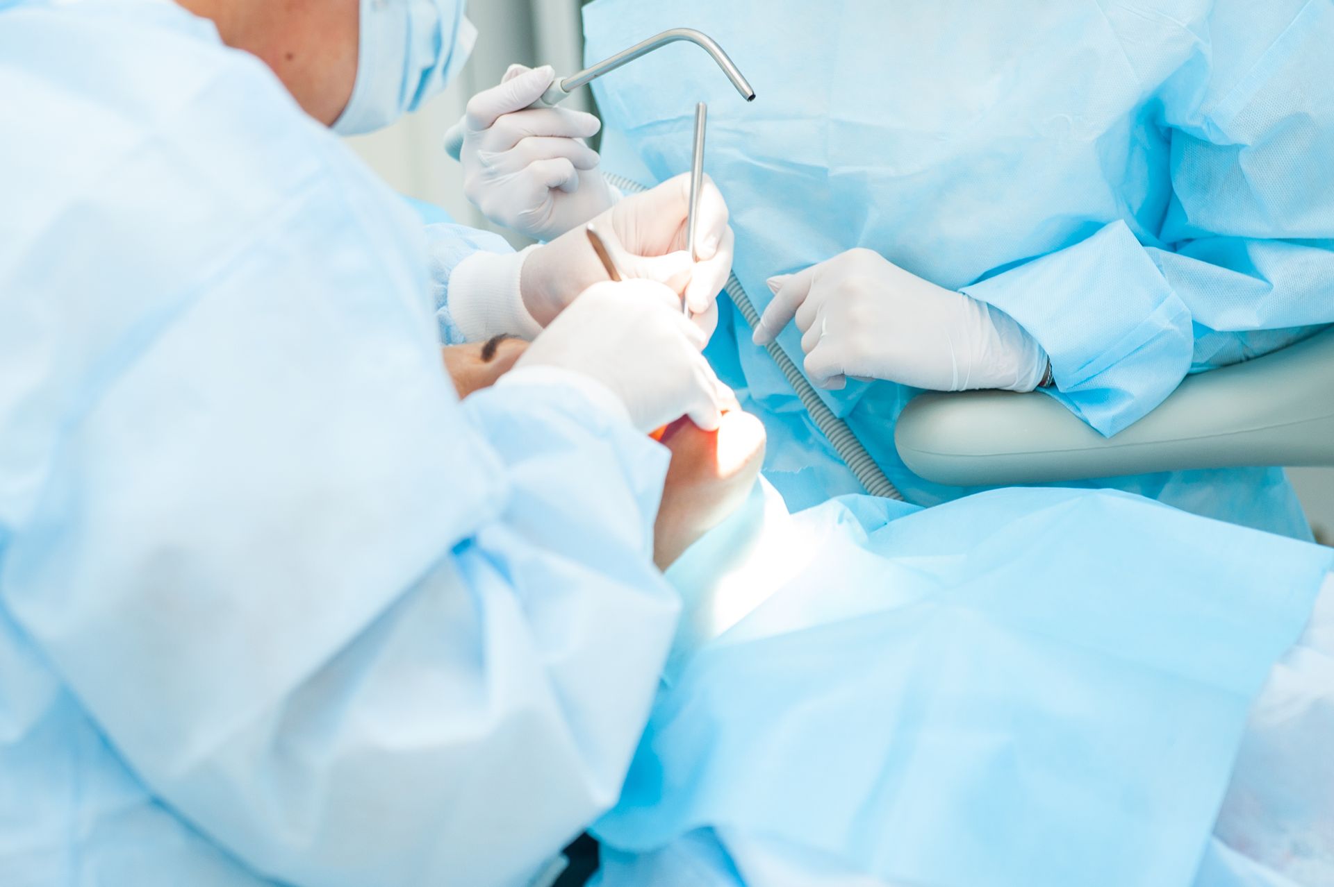 Dentist in mask examining patient's teeth in dental chair with equipment.