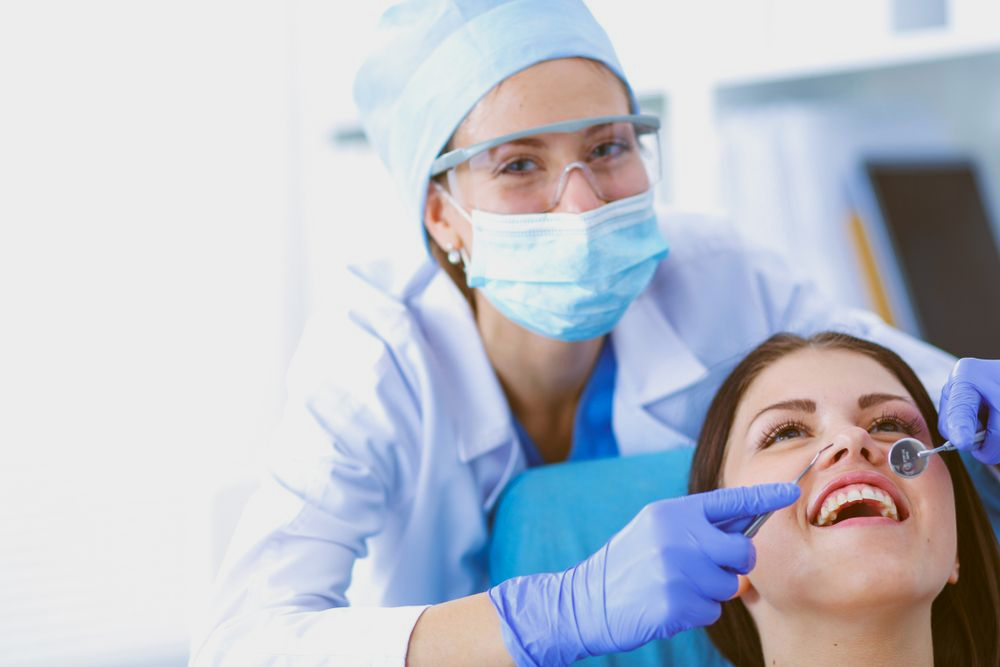Dentist examining a patient's teeth with a mirror in a dental office.