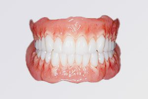 Person calculating dental costs with a calculator and clipboard near a large tooth model and laptop.