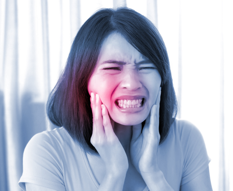 Woman with pained expression, holding cheeks, highlighting red pain on left cheek; indicating possible dental issue.