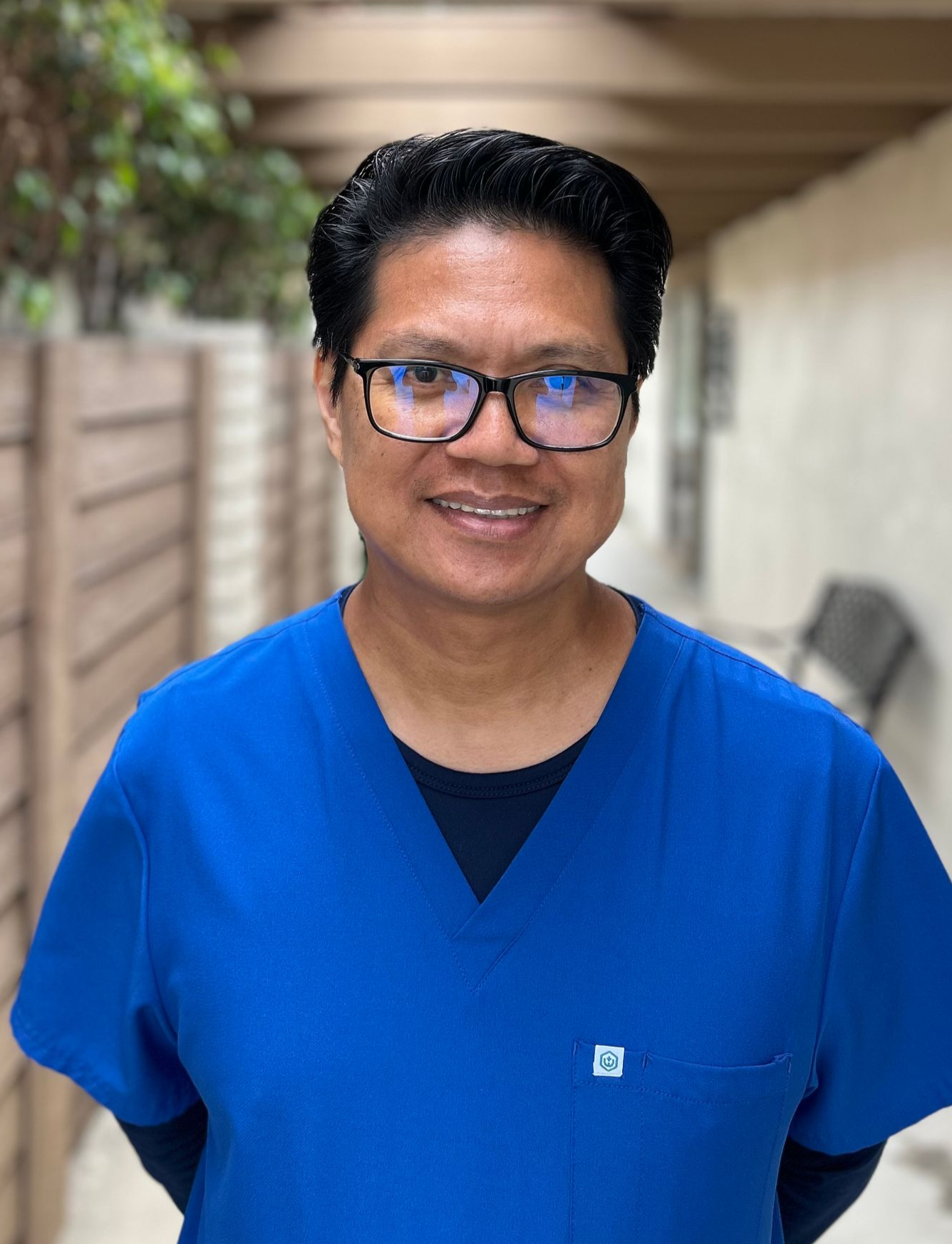Smiling person in a dark blue top, standing outdoors.