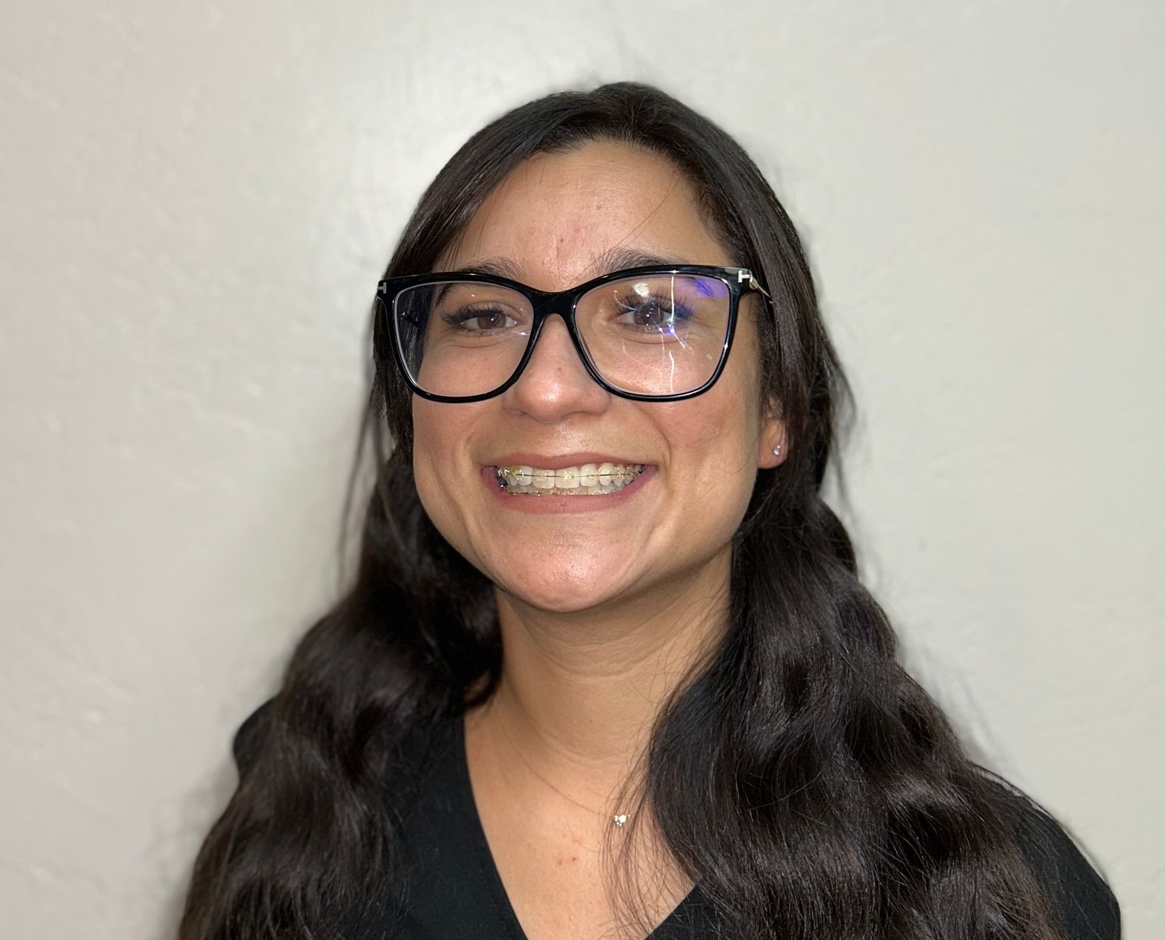 Woman in blue scrubs smiles, office setting, blonde hair.