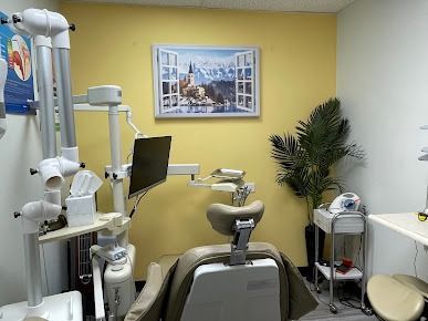Dental office room with dental chair, equipment, and a wall-mounted TV.