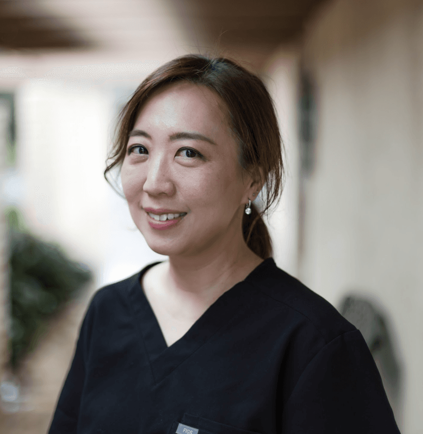 Smiling person in a dark blue top, standing outdoors.