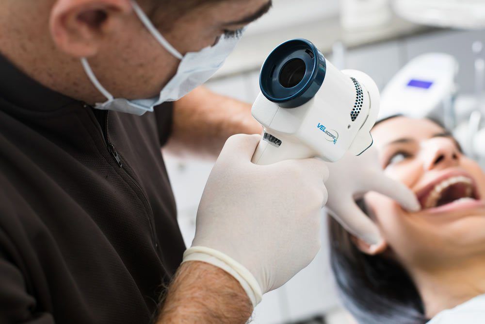 Dentist using intraoral camera on patient. Patient has mouth open.