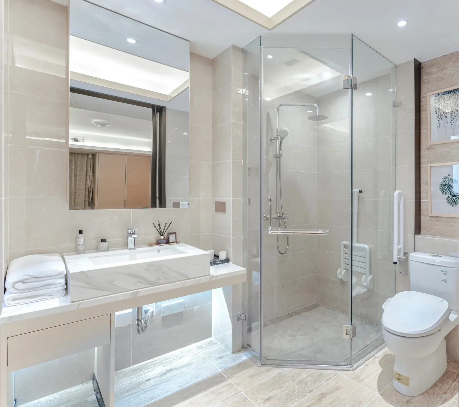 Modern bathroom with a marble sink, glass shower, and toilet. Beige tile walls.