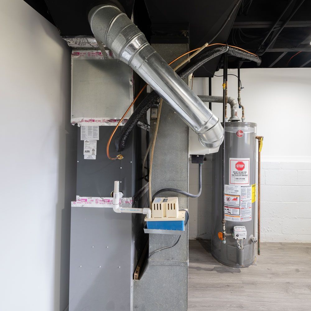 Furnace and water heater in a utility room. Gray metal appliances against white walls.