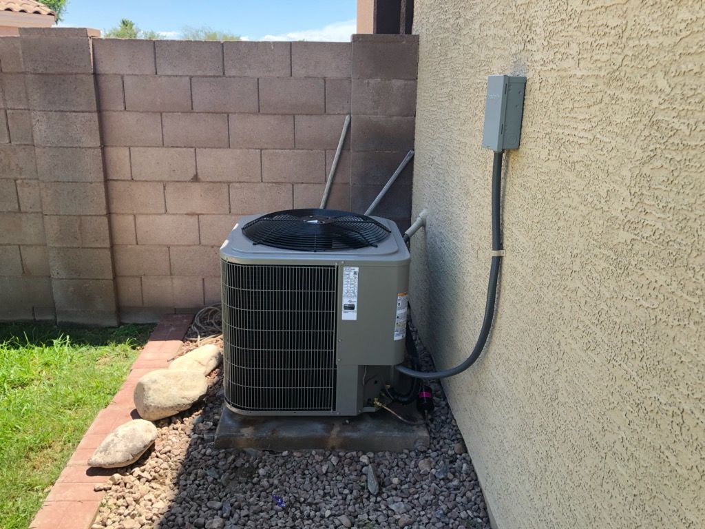An air conditioner is sitting on the side of a building next to a brick wall.