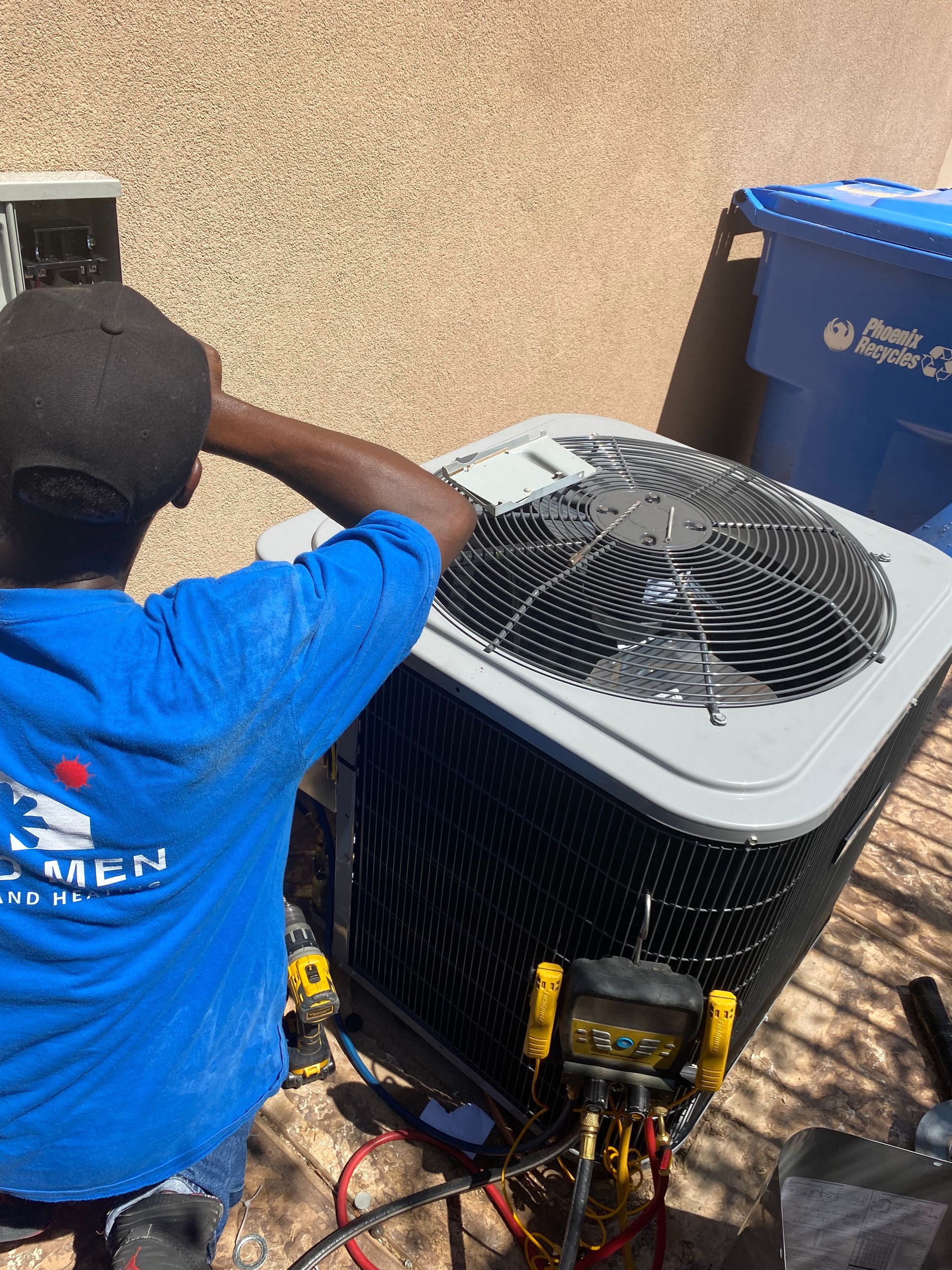 A man in a blue shirt is working on an air conditioner.