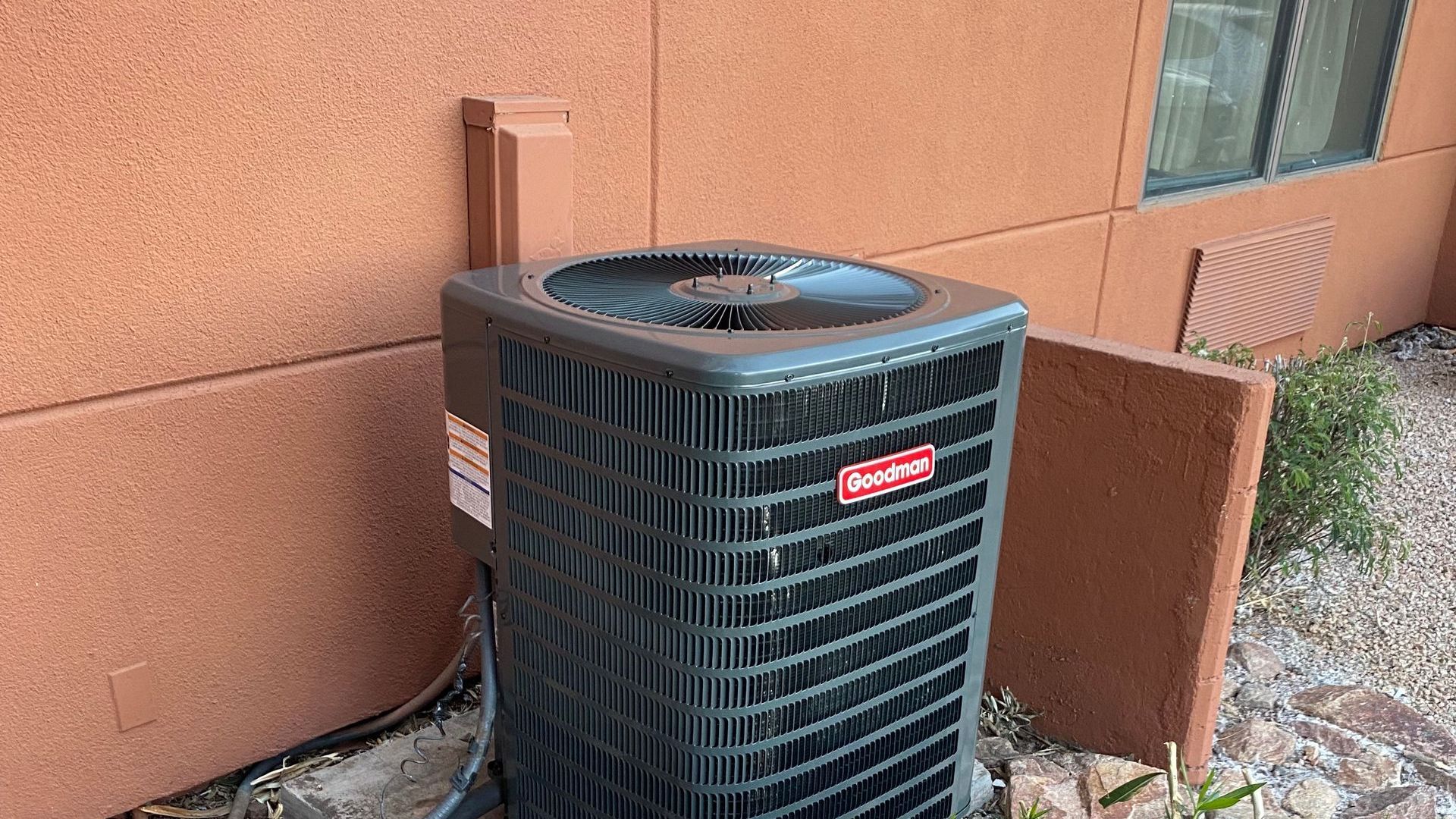 A black air conditioner is sitting on the side of a building.
