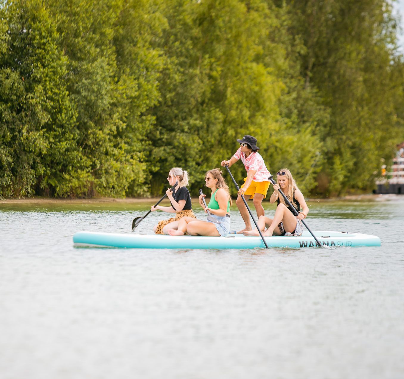 Een groep mensen rijdt op een mega paddleboard op een meer.