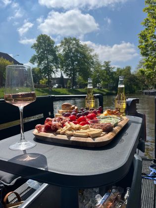 Een tafel met daarop een dienblad met eten en een glas wijn.