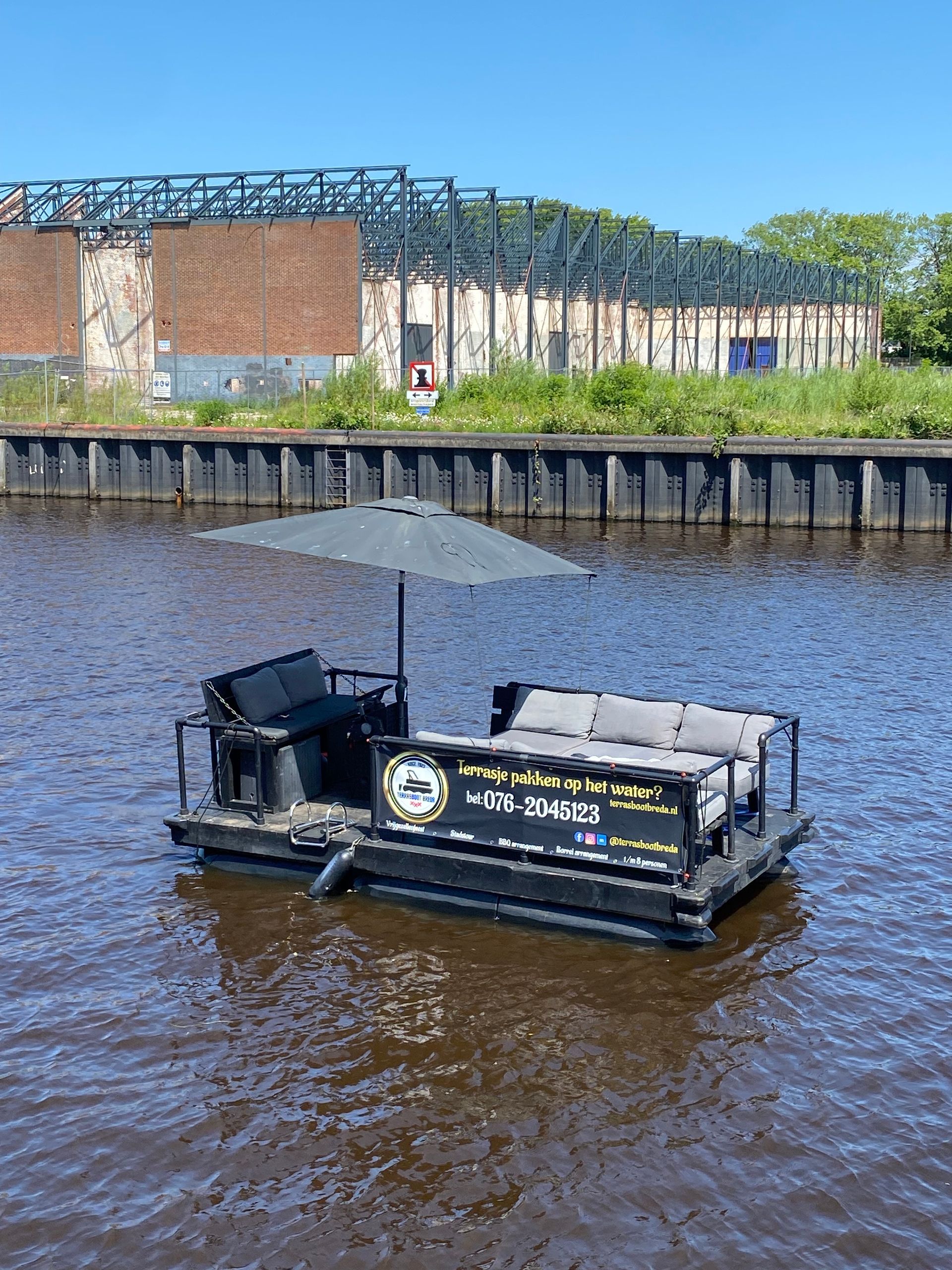 Een boot met een bank en een parasol drijft op een watermassa