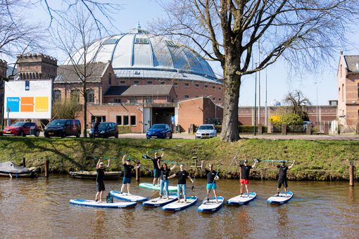 Een groep mensen staat op paddleboards in het water.