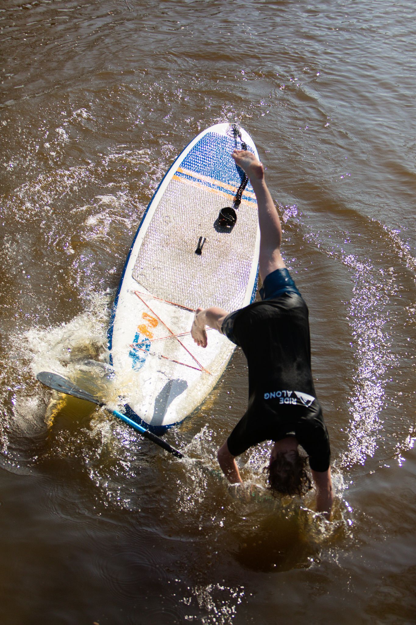 Een man doet een handstand op een surfplank in het water.