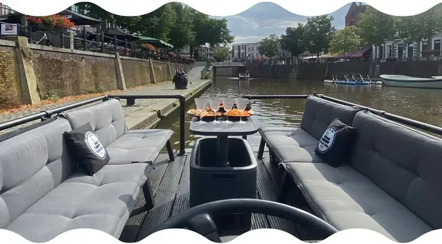 Uitzicht vanaf de terrasboot op Breda. Met gebouwen en een kerktoren in de verte.