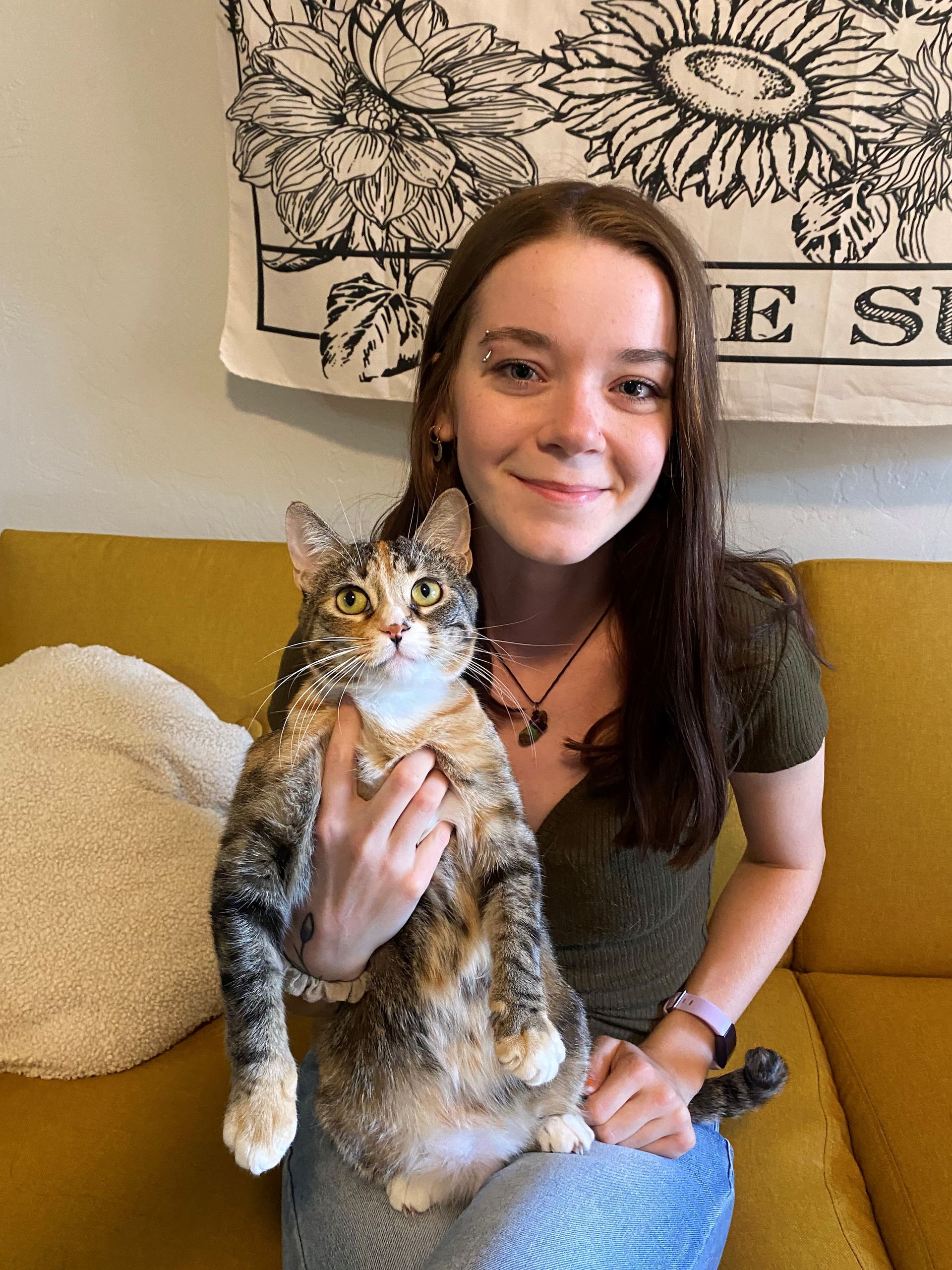 A woman is sitting on a couch holding a cat.