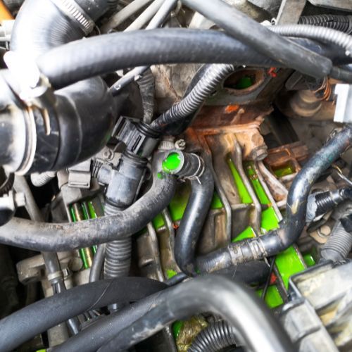 A close up of a car engine with green liquid coming out of it