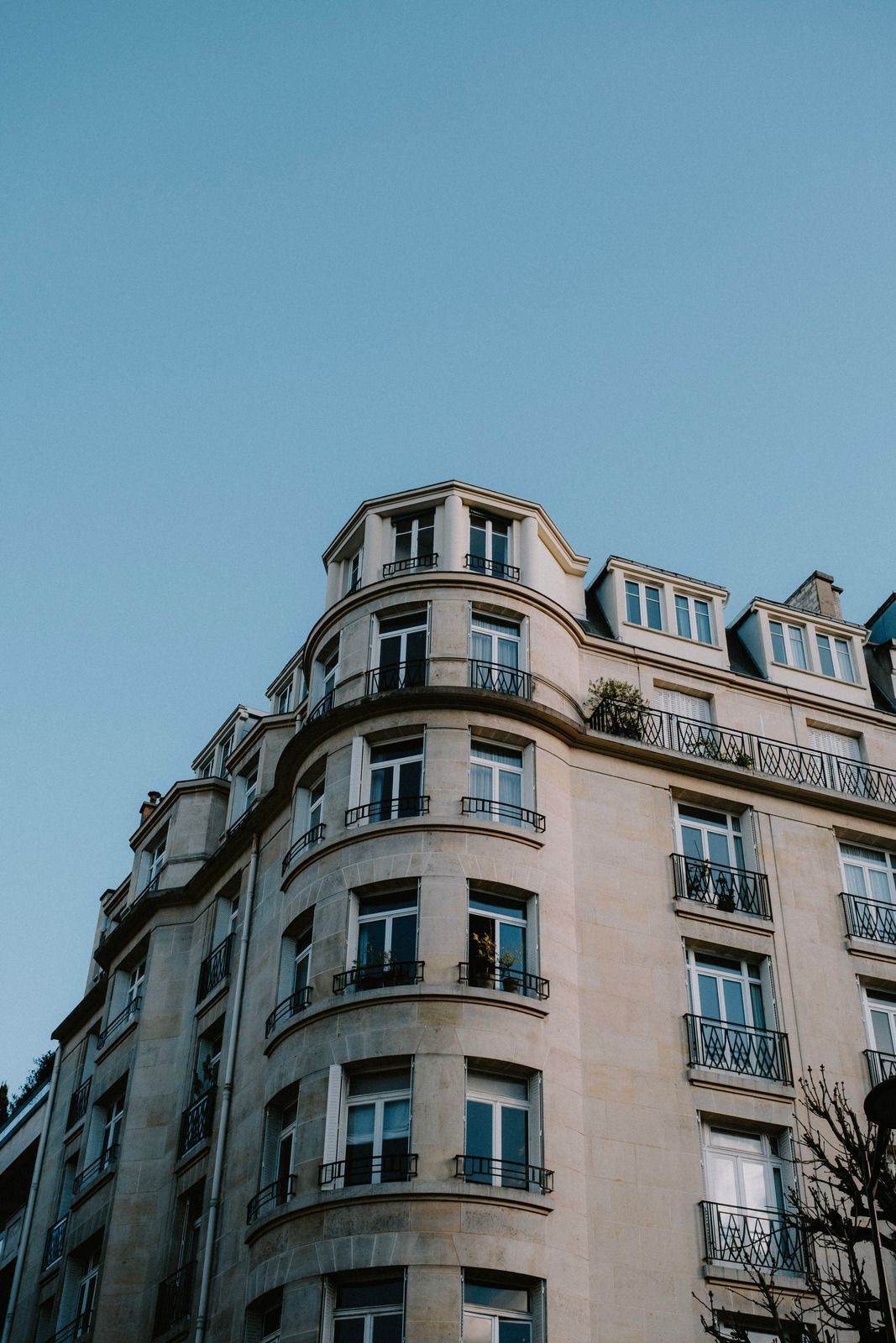 Corner of a pale stone apartment building against a clear blue sky
