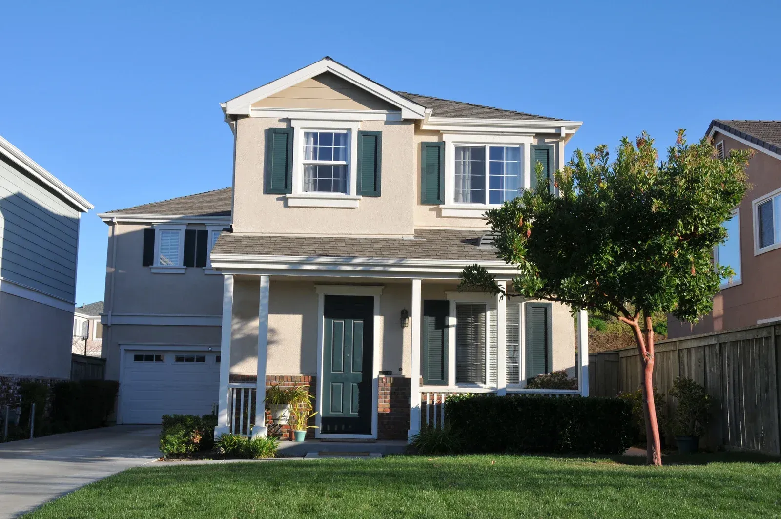 A house with a porch and a tree in front of it