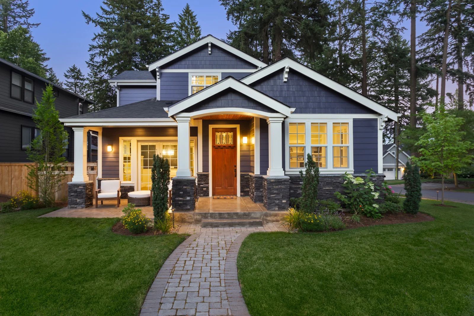 Blue house with white trim, stone accents, and a red front door; path leads to entrance.