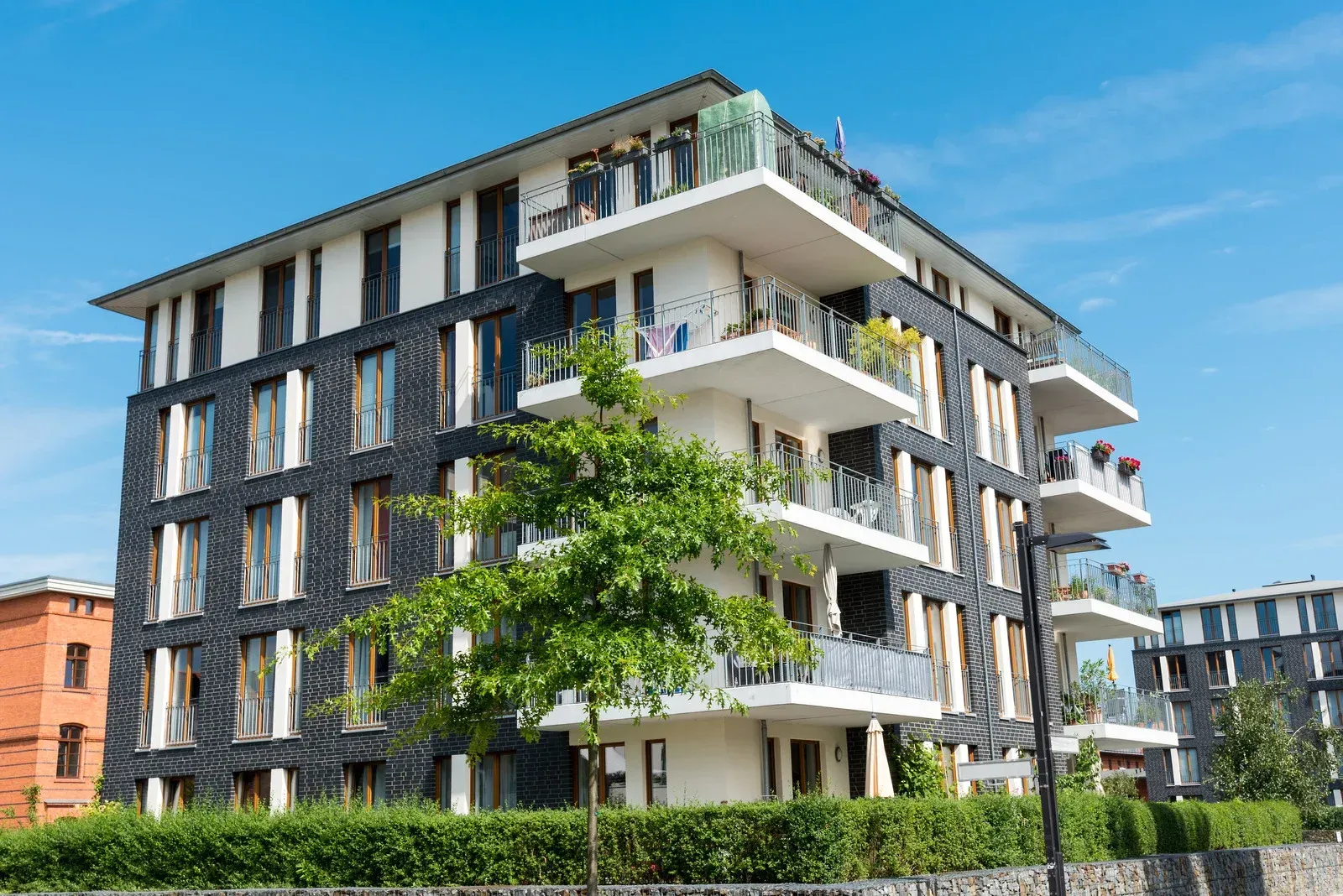 A large apartment building with lots of balconies and trees in front of it.