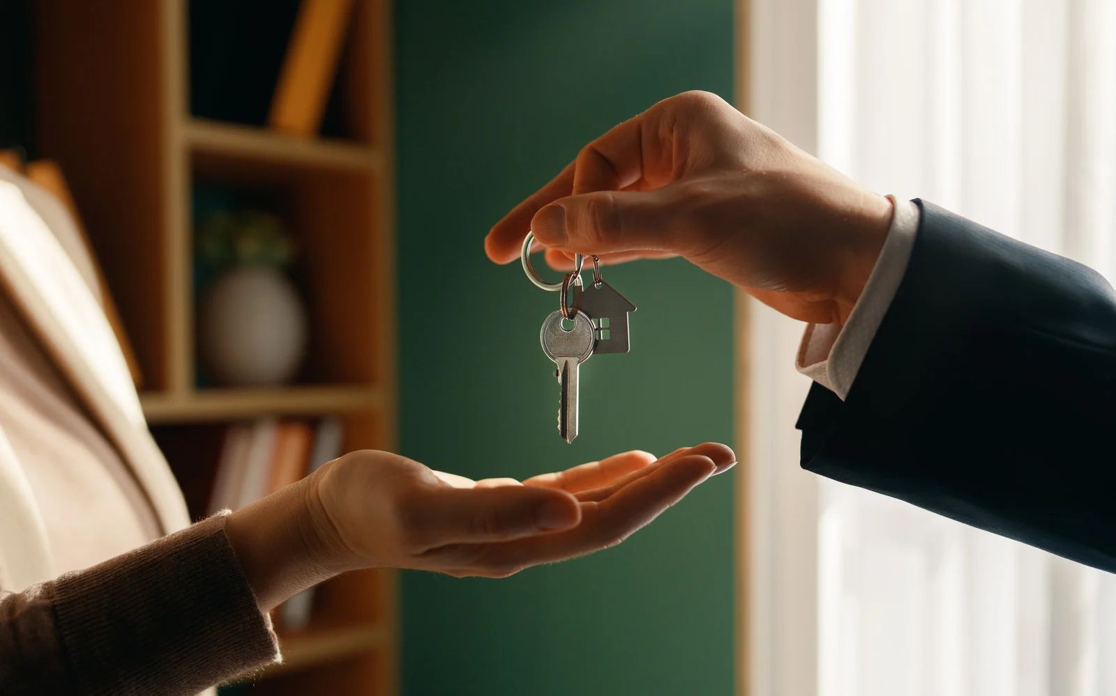 Person handing house keys to another person.