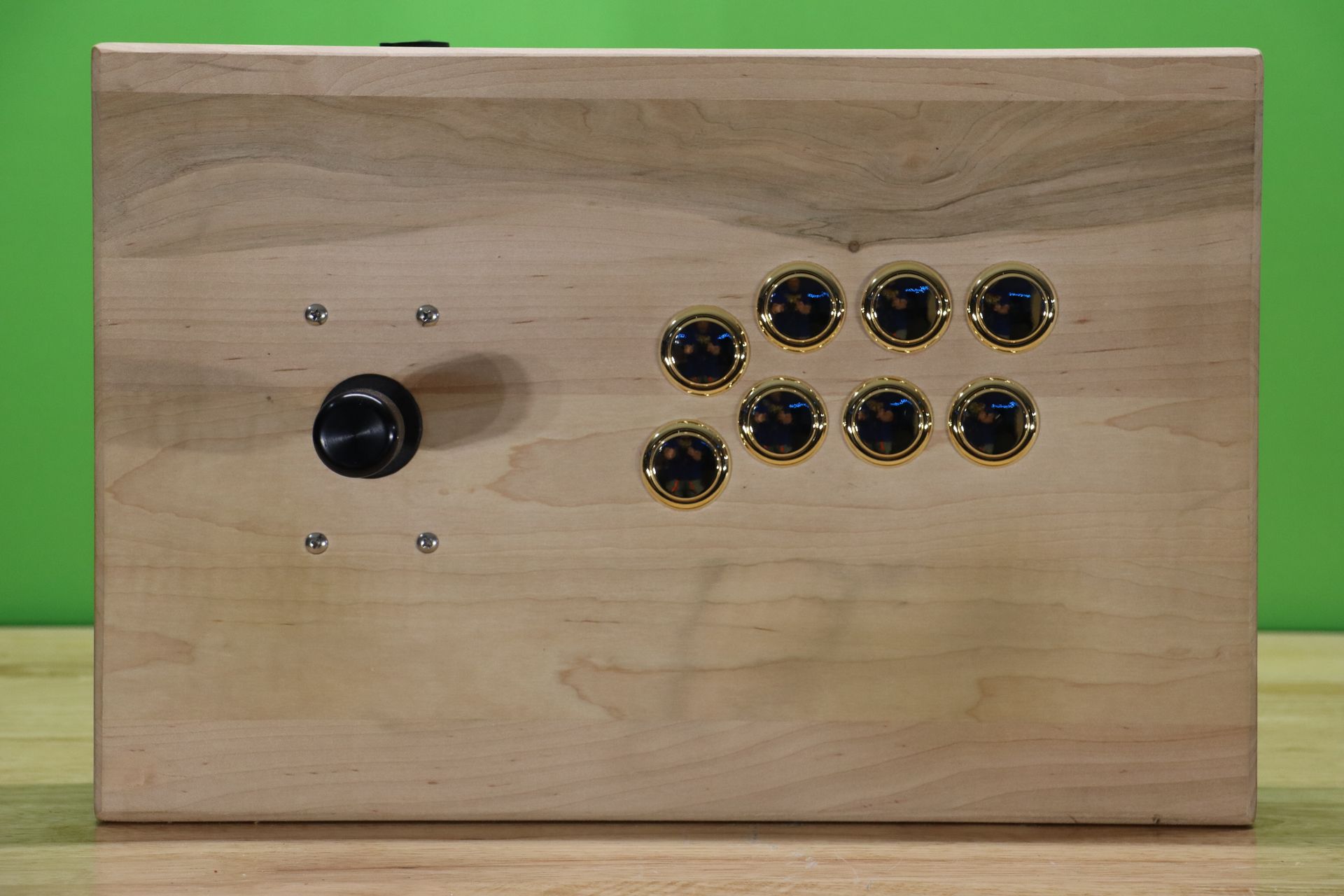 A wooden box with buttons on it is sitting on a wooden table.