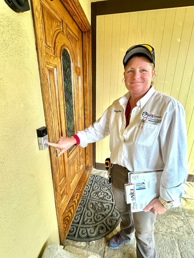 Person in work attire rings doorbell of ornate wooden door.