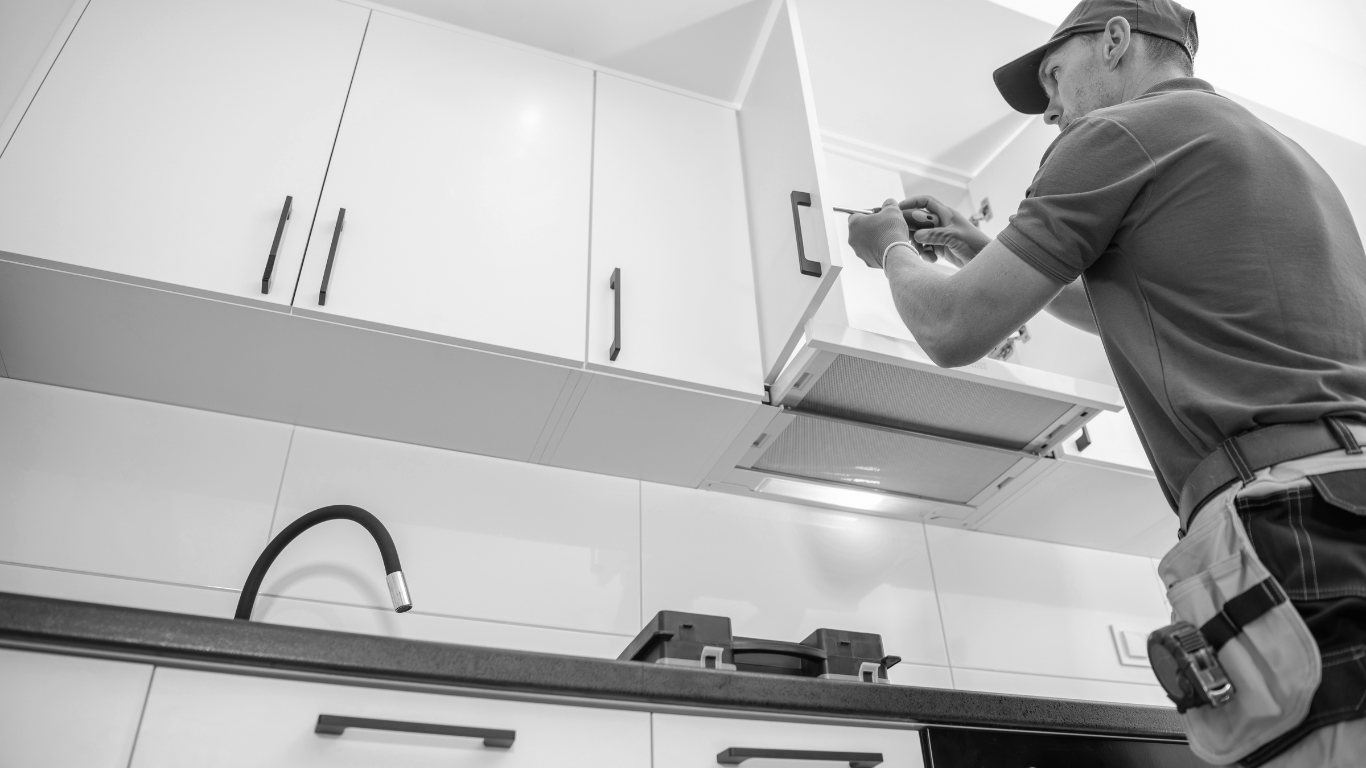 A man is installing a hood in a kitchen.