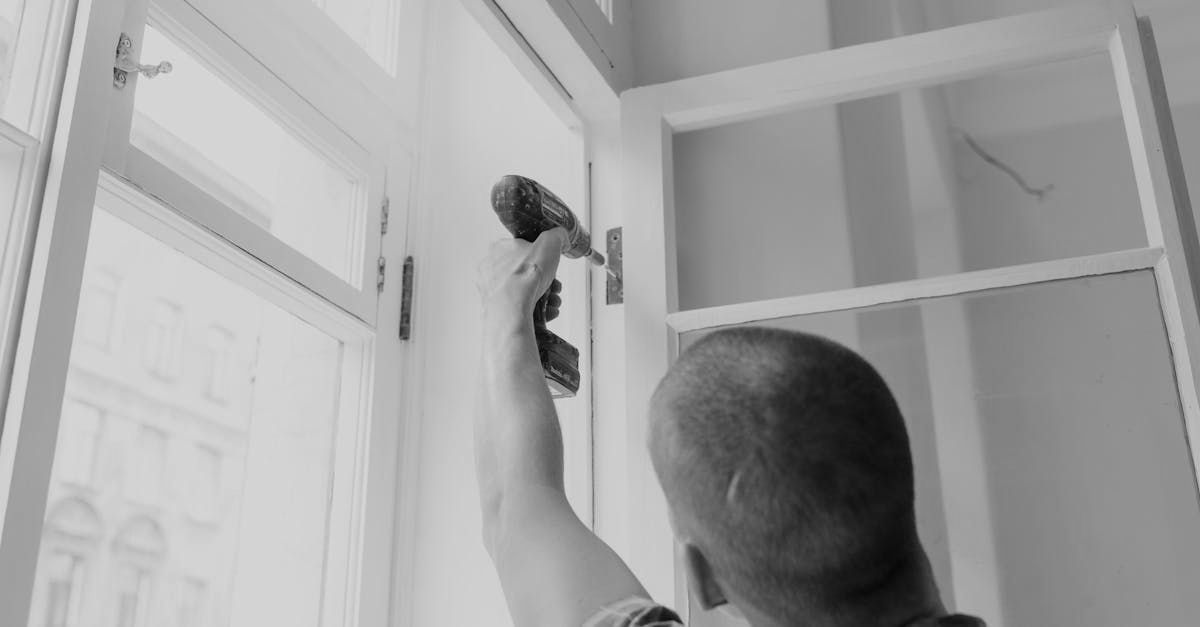 A man is using a drill to fix a window.