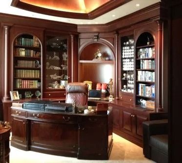 A luxurious home office with dark wood desk, bookshelves, and a leather chair.