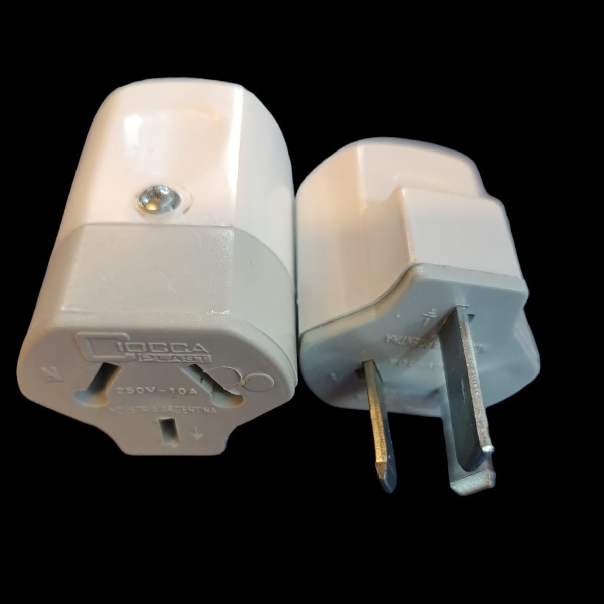 Dos adaptadores de enchufe eléctrico de color blanco y gris sobre un fondo negro.