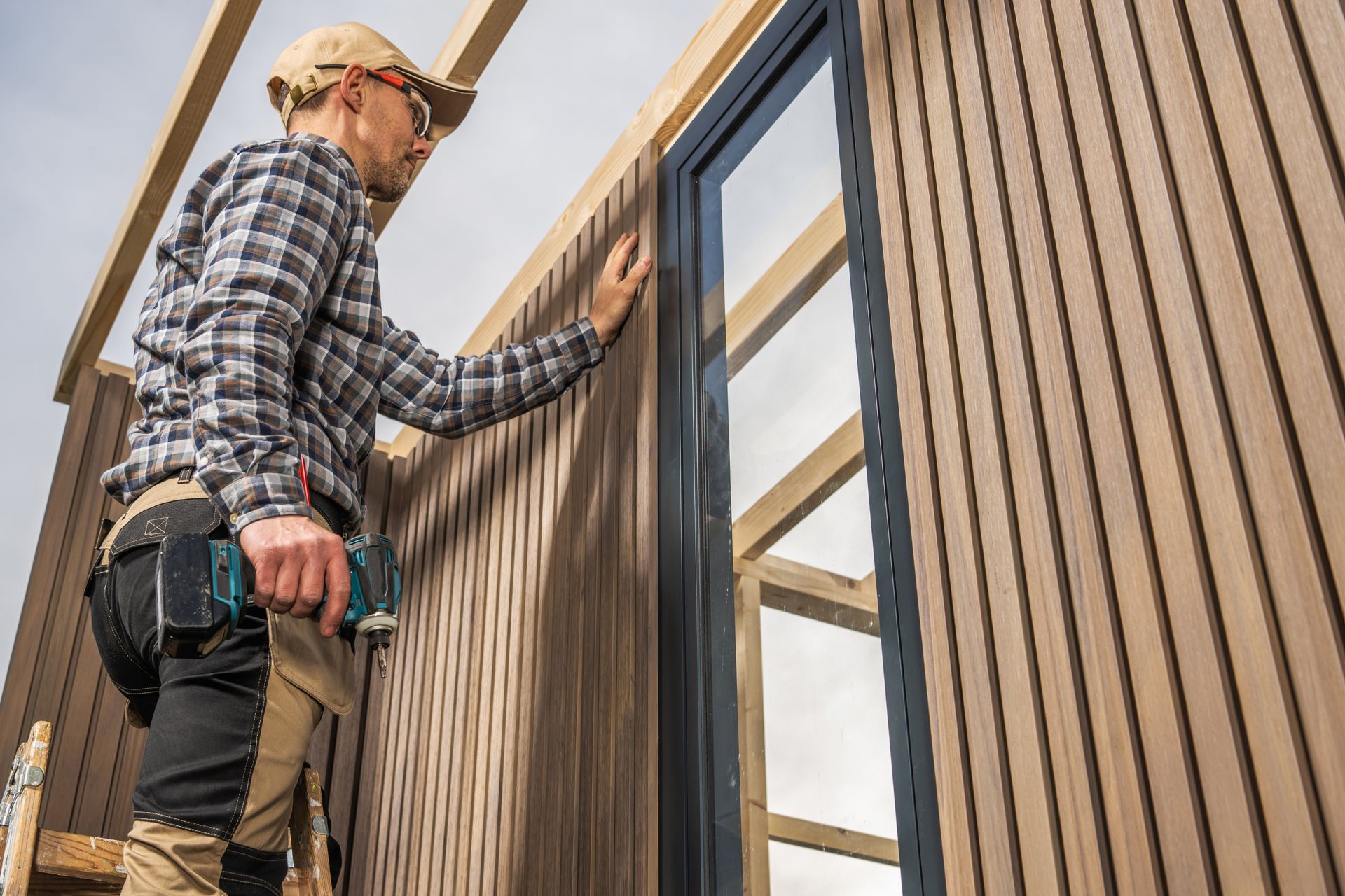 Un homme installe une fenêtre sur le côté d'un bâtiment.