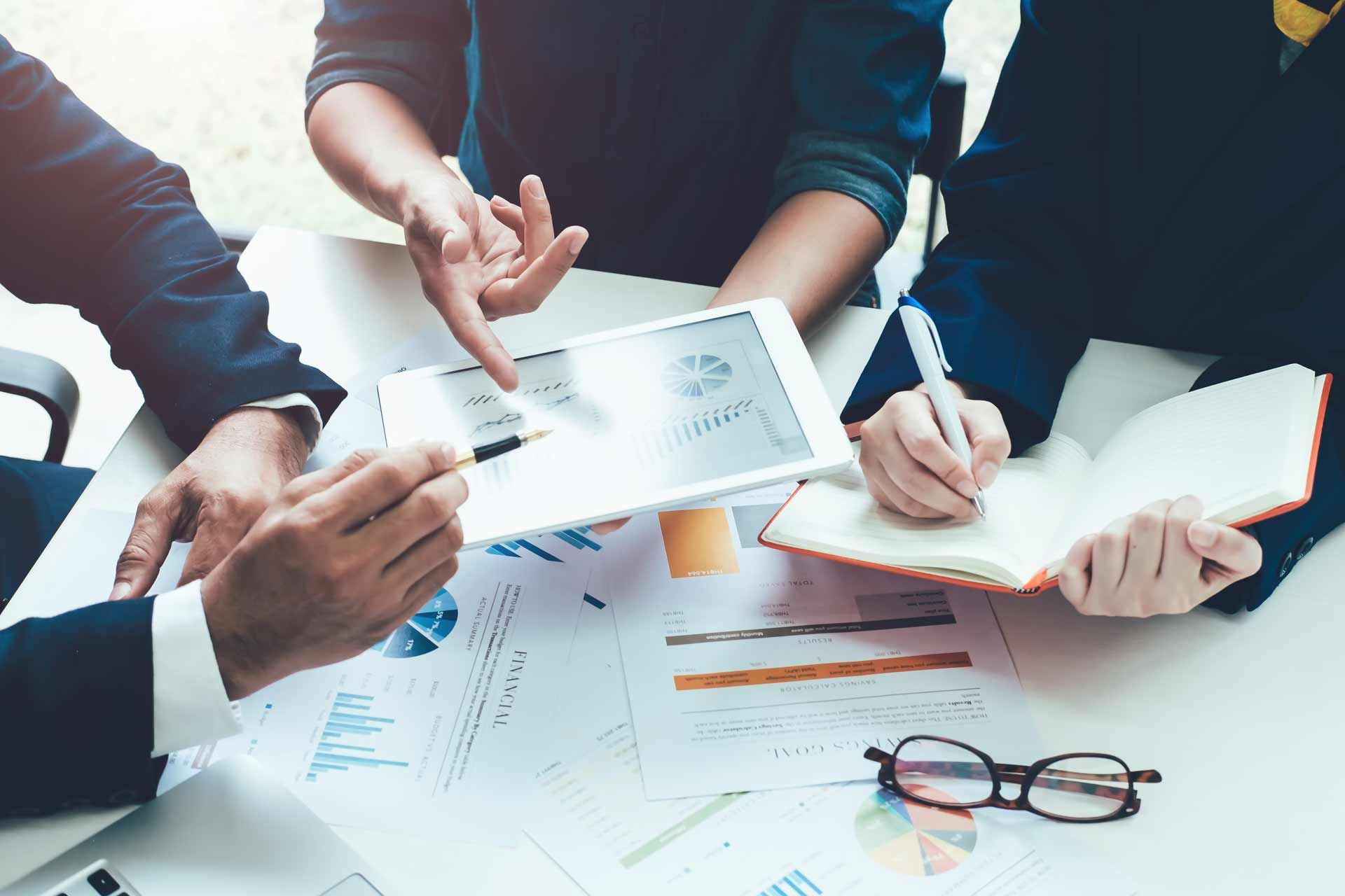 People reviewing financial reports on tablet and paper at a table