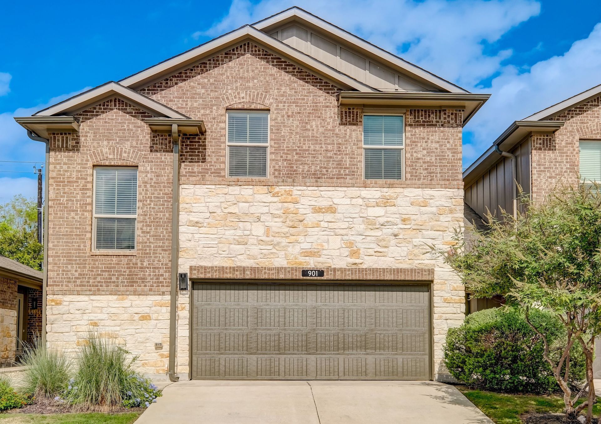 Two-story house with brick and stone facade, two-car garage, and small front yard.