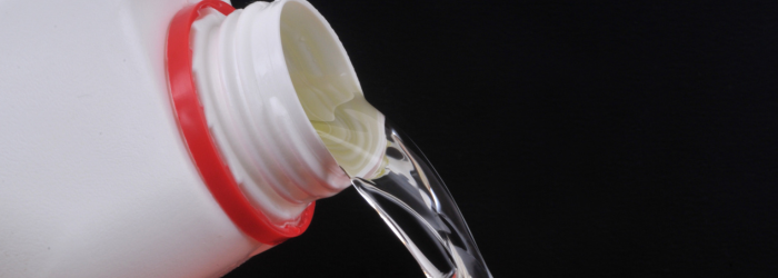 Liquid pouring from a white container with a red ring against a black background.