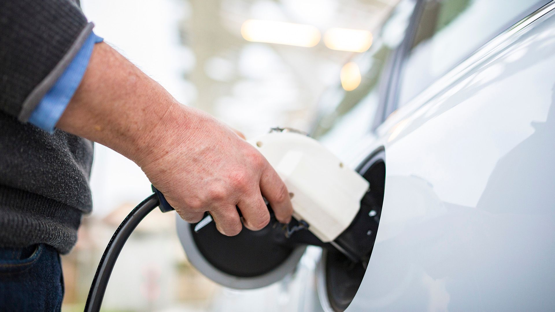 A man is charging his electric car at a charging station.