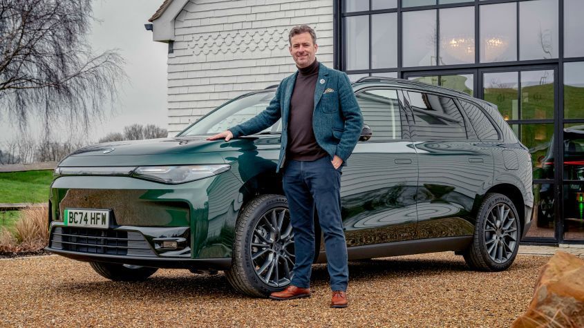 Dark green LEAPMOTOR arked outside a house with a middleaged man stood beside it