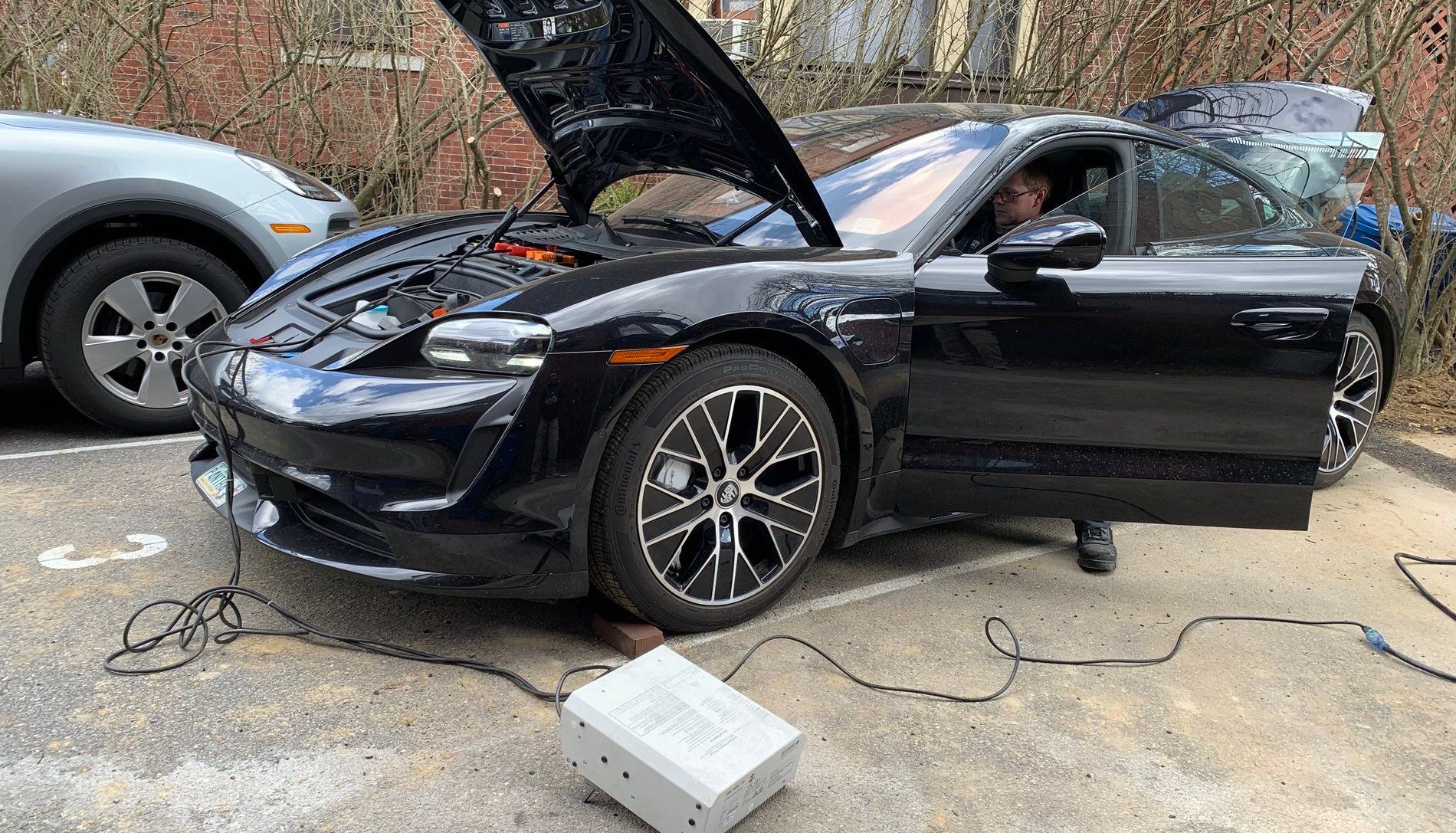 a black Porsche Taycan is being charged in a car park. 