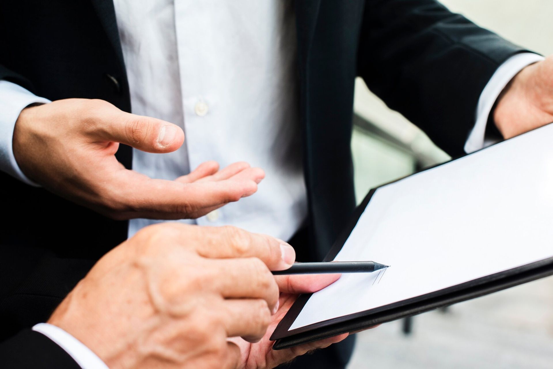 Two men are looking at a piece of paper with a pen.