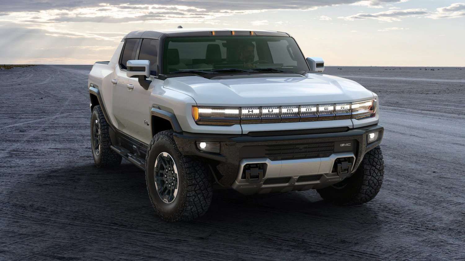 A white hummer electric vehicle truck is parked on a dirt road.