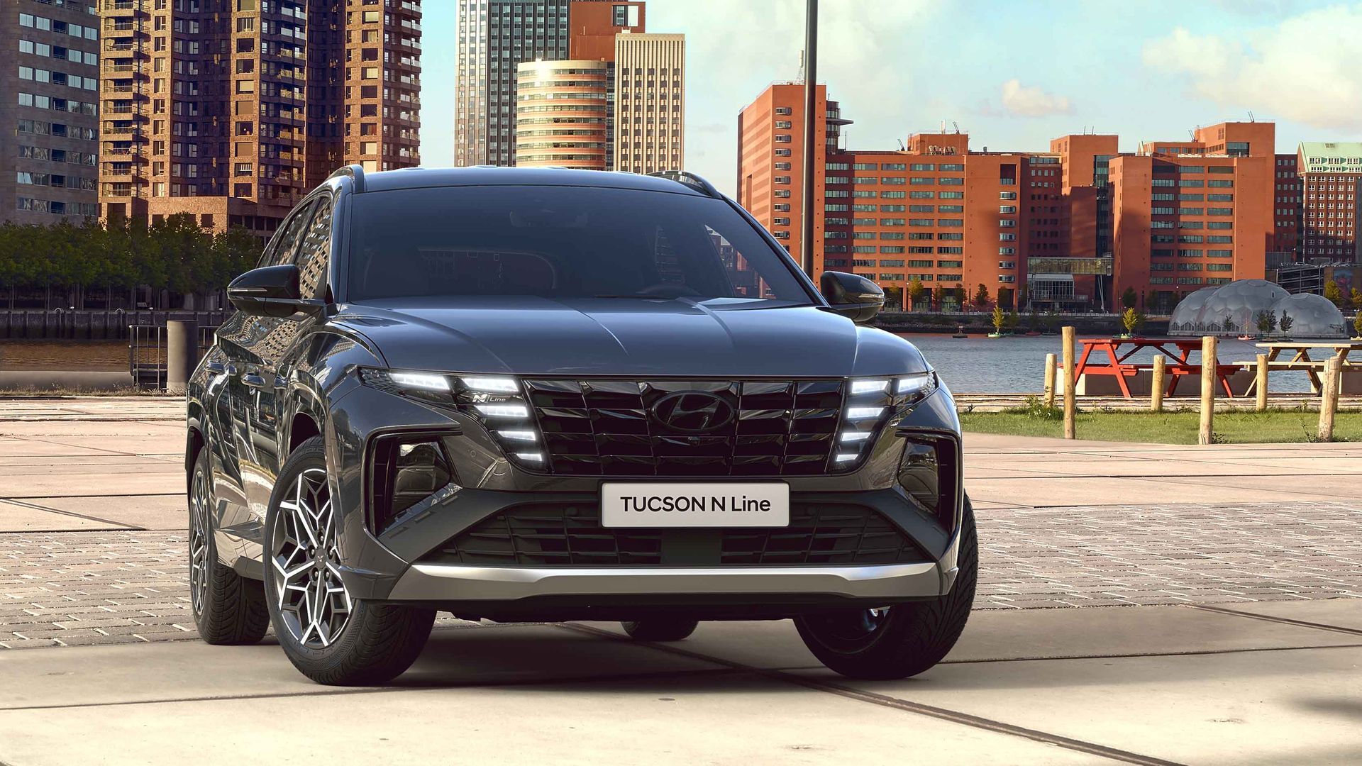 A black Hyundai Tucson is parked in front of a city skyline.