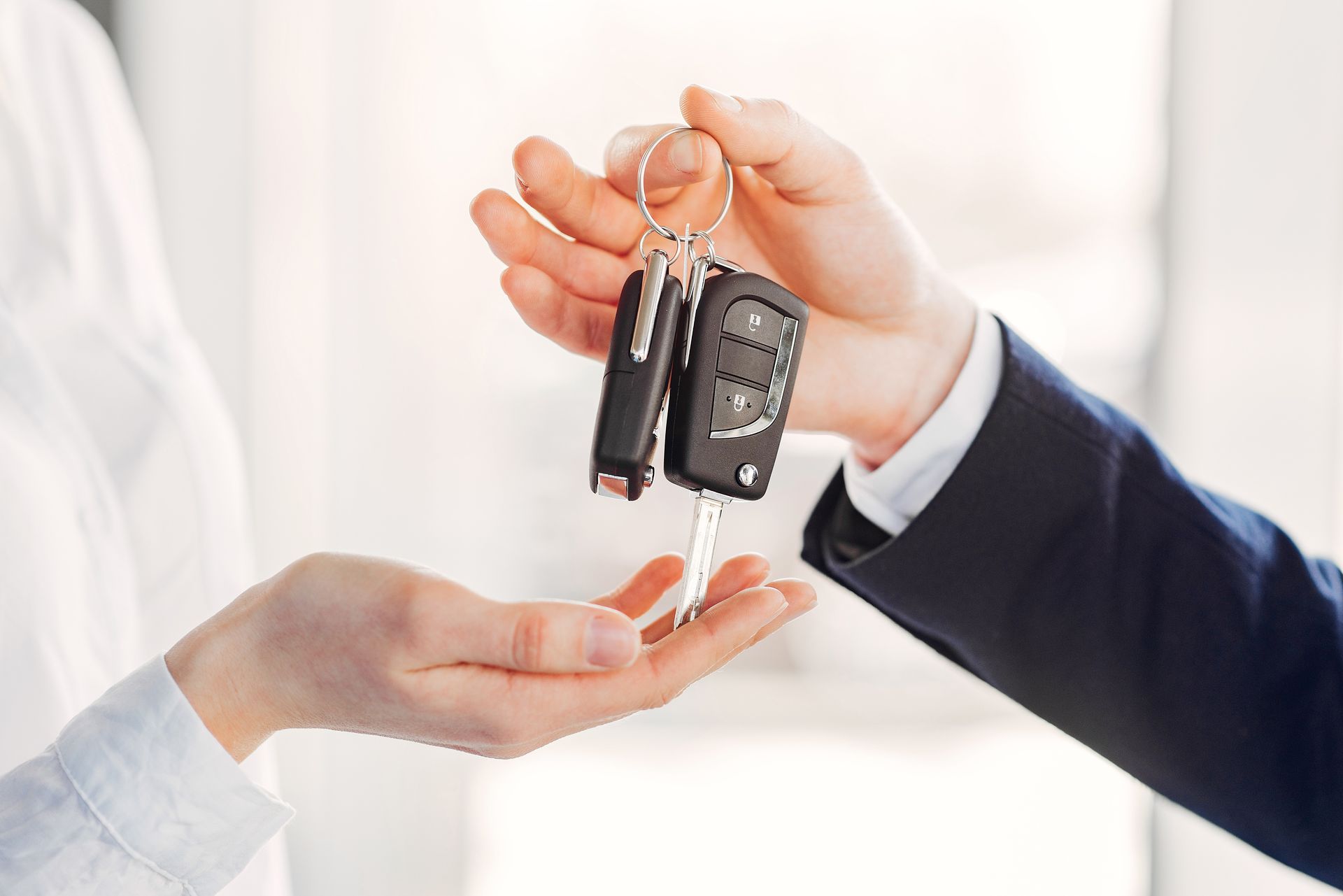 A man is handing a car key to a woman.