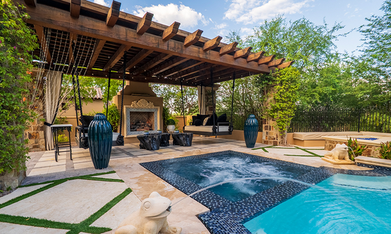 Backyard patio with pergola, lounge seating, and a swimming pool beside lush greenery