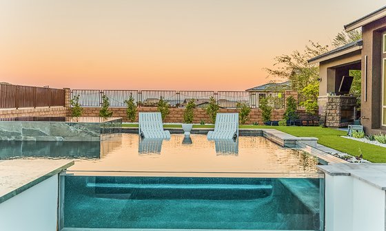 Modern backyard pool with two blue chairs on a sun deck at sunset