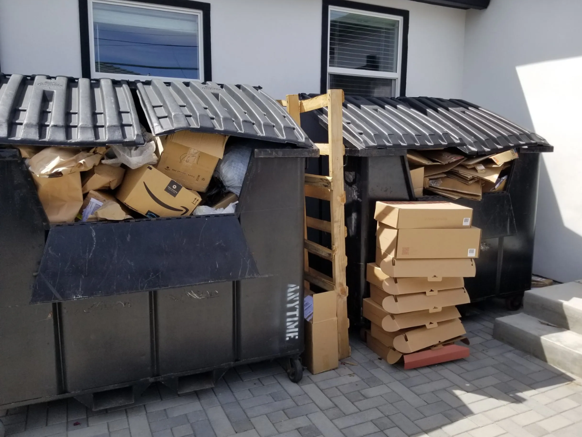 Two overflowing dumpsters filled with cardboard boxes.