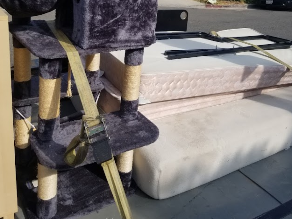 Cat tree and mattresses secured on a vehicle with straps.