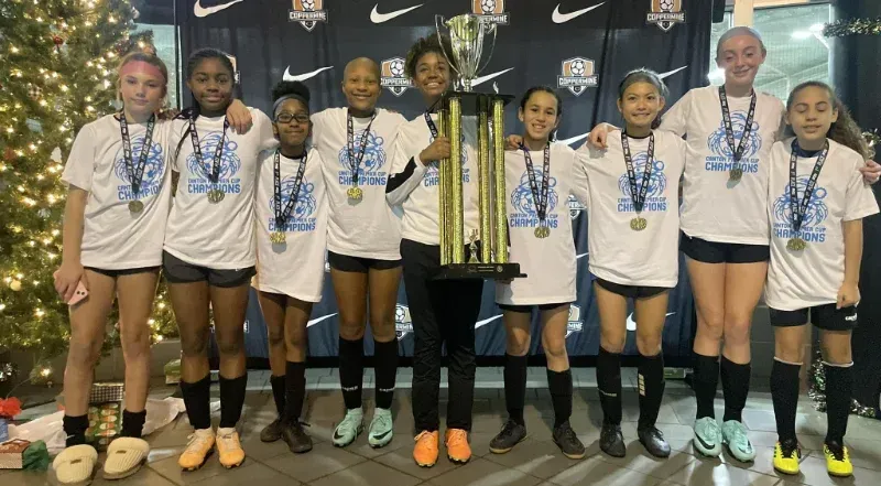 A group of young girls are posing for a picture with a trophy.