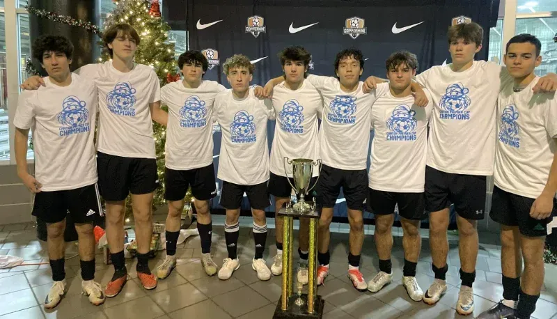 A group of young men are posing for a picture with a trophy.